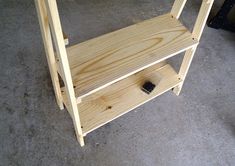 a wooden shelf sitting on top of a carpeted floor next to a black object