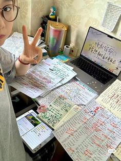 a young boy sitting at a desk with lots of papers and writing on the table