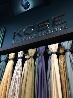 an assortment of different colored ties hanging on a rack in front of a sign that reads kole international design