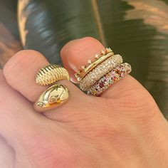 a person's hand with three rings on top of each other and one has a gold shell