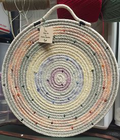 a woven basket is on display in a room with yarns and other crafting supplies