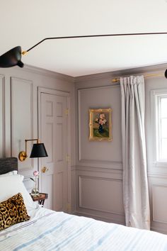 a bedroom with gray walls and white bedding, two lamps on either side of the bed