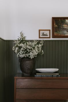 a vase filled with flowers sitting on top of a wooden dresser