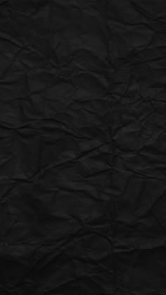 a black paper textured background that is slightly wrinkled out and has been used as a backdrop