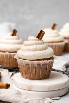 cinnamon spice cupcakes with white frosting and cinnamon sticks sticking out of them