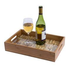 a bottle of wine and a glass on a wooden tray with corks in it