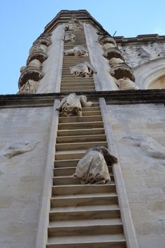 a tall building with statues on it's side and stairs leading up to the top