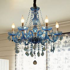 a blue chandelier hanging from the ceiling in a room with curtains and windows