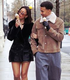 a man and woman walking down the street eating ice cream