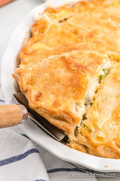 a close up of a pie in a pan on a table with a wooden spoon