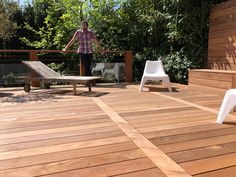 a man standing on top of a wooden deck next to two white chairs and a table