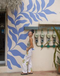 a woman standing in front of a wall painted with blue and white designs on it