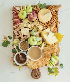 a platter with apples, crackers, cheese and other food items on it