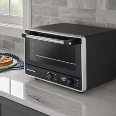 a toaster oven sitting on top of a counter next to a plate with pizza