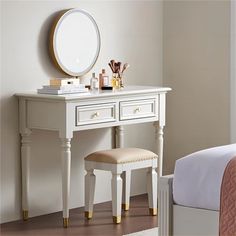 a white vanity table with a mirror and stool next to it on top of a bed