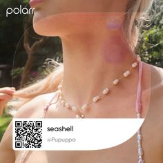 a woman wearing a pink necklace with pearls on it and a qr code attached to her chest