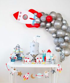 a space themed birthday party with silver balloons and red rocket ship balloon wall hanging on the wall