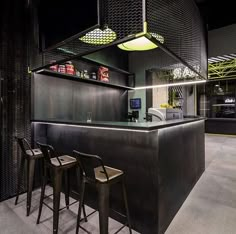 a bar with three stools in front of it and lights hanging from the ceiling