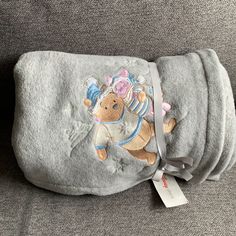 a baby blanket with a teddy bear on it and a tag attached to the back