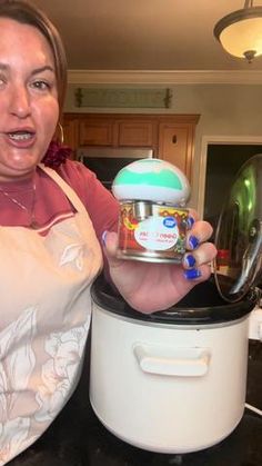 a woman holding an ice cream container in her hand while standing next to a crock pot