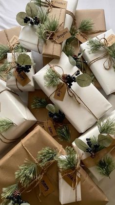 many wrapped presents are stacked on top of each other with evergreen leaves and pine cones