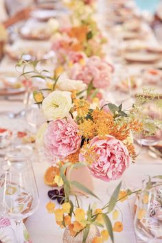 a long table with flowers and wine glasses on it