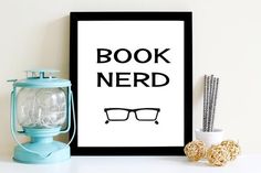 a framed poster with the words book nerd next to it on a table top