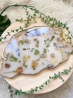 a platter with dried flowers and leaves on it sitting on a white furnishing