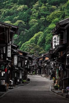 an alley way with buildings and mountains in the background, surrounded by greenery on both sides