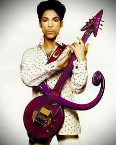 prince is holding a purple guitar in his right hand