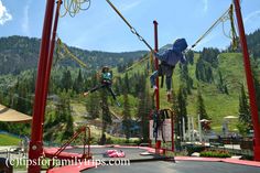 two people are doing aerial tricks in the air on a trampoline course with mountains in the background