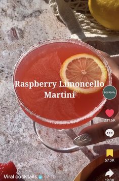 a person holding a drink with a lemon slice on the rim and text reading raspberry limoonello martini