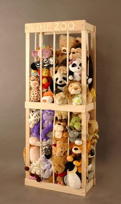 a wooden shelf filled with lots of stuffed animals on top of a floor next to a wall