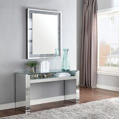 a white table with a mirror and vase on it in front of a gray wall