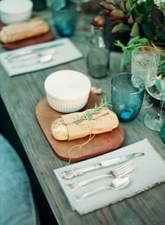 a wooden table topped with plates and silverware