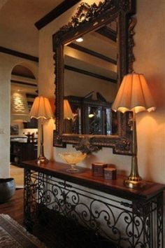 a large mirror sitting on top of a wooden table next to two lamps and a lamp