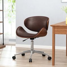 a black office chair sitting on top of a wooden floor next to a table and bookshelf