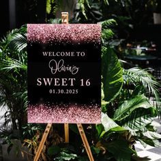 a welcome sign sitting on top of a wooden easel in front of some plants