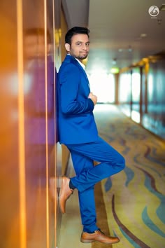 a man in a blue suit leaning against a wall