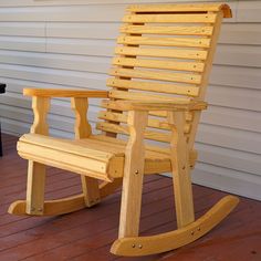 a wooden rocking chair sitting on top of a red brick floor next to a white house