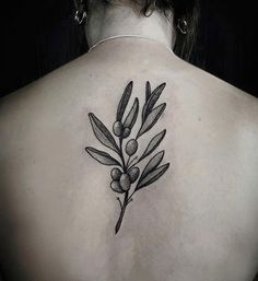 the back of a woman's shoulder with an olive branch tattoo design on it