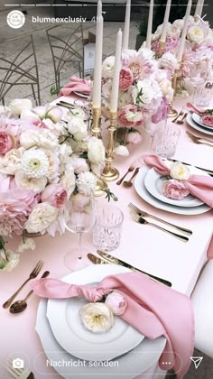 the table is set with pink and white flowers, silverware, and napkins