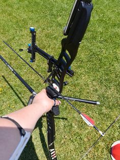 someone is holding their bow and aiming it at the target on the ground in the grass