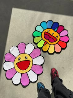 two flower shaped rugs on the ground with someone's feet in black shoes