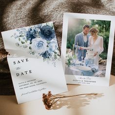 two wedding cards with blue flowers on them next to a flower bouquet and an envelope