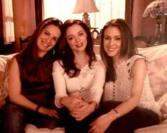 three women sitting on a couch smiling for the camera