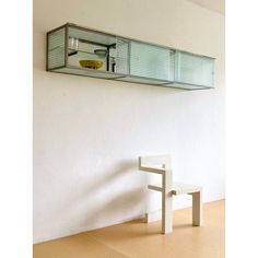 a white chair sitting in front of a glass shelf on the wall next to a table