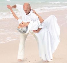 a man and woman dancing on the beach