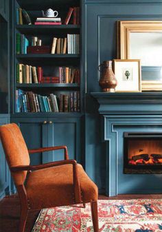 a living room with blue walls and a fire place in the center, bookshelves on either side