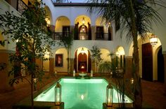 an indoor swimming pool in the middle of a courtyard with potted plants and lights